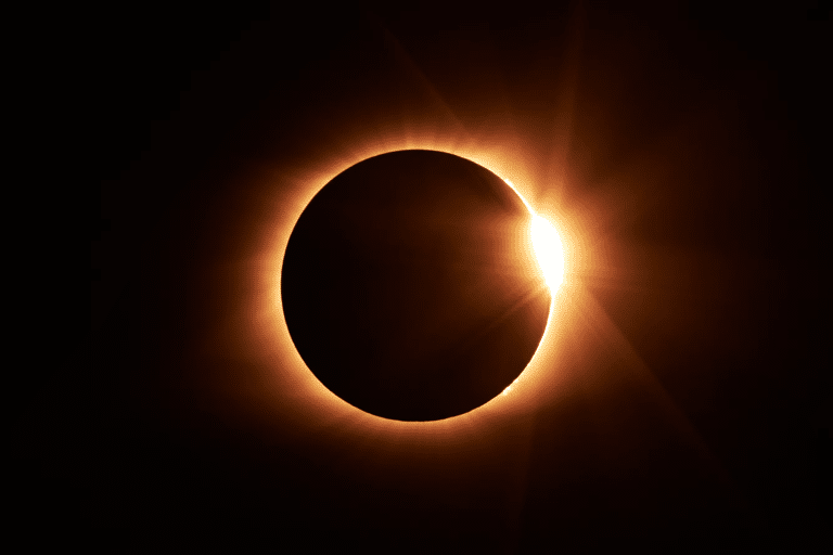 Bright diamond-ring effect at the edge of the Moon during a solar eclipse.